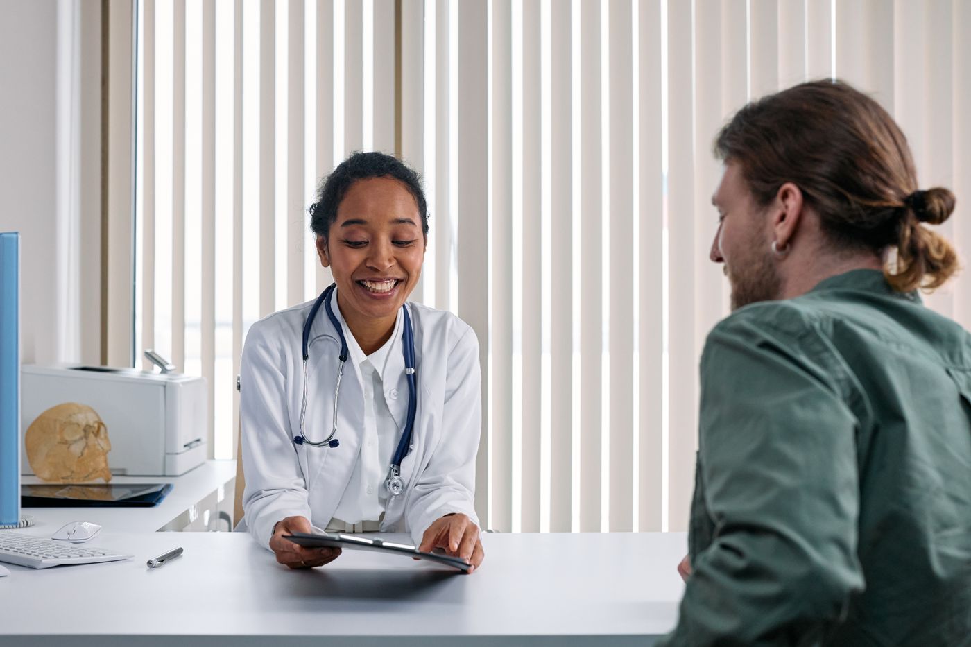 Médica sorridente conversando com um paciente durante a consulta