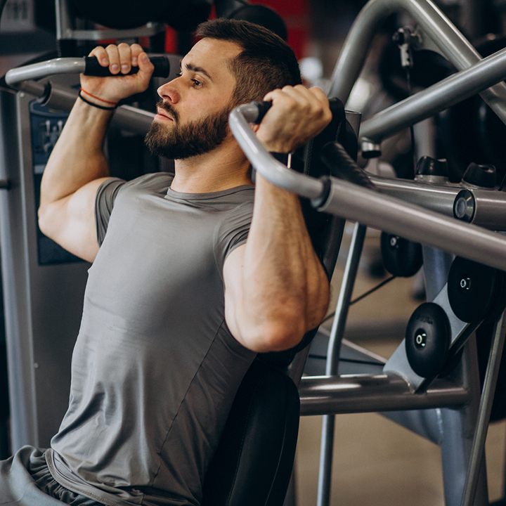 Homem treinando em um aparelho de musculação na academia
